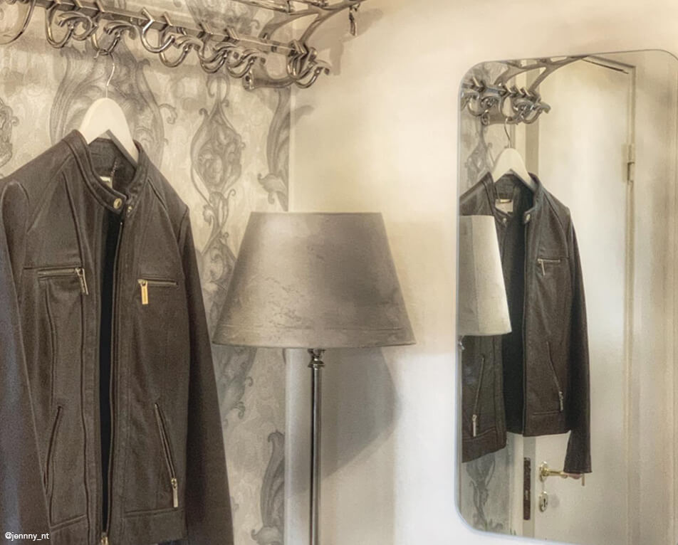 Esiku sisustus – metallist nagid, ristkülikukujuline peegel ja hall lamp